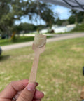 Hand holding a wooden sample spatula with a swatch of Repair & Nurture Skin Balm, outdoors on grass