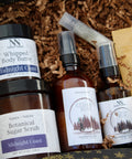 Natura+Nutrire gift collection with Whipped Body Butter, Botanical Sugar Scrub, and Cedar Rum Magnesium Lotion and Spray, nestled in brown crinkle paper