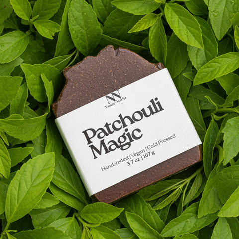 Patchouli Magic Vegan Soap bar with kraft paper label resting on a bed of green leaves