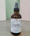 Cucumber Facial Toner with Rice Ceramides bottle standing on a concrete surface against a mint green and pink backdrop