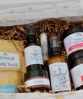 Natura+Nutrire gift box with Whipped Body Butter in Strawberry Coco, Botanical Sugar Scrub, Serenity Magnesium Lotion, Magnesium Spray, Mineral Bath Soak, Rose Renewal Clay Mask, and a lip balm, in white star-patterned tissue paper