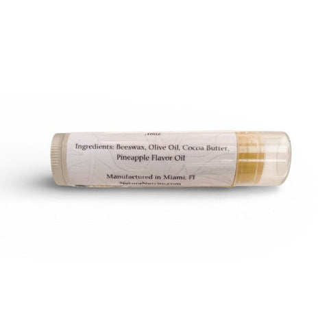 Tropics Pineapple Olive Oil Lip Balm tube showing ingredients label listing beeswax, olive oil, cocoa butter, and pineapple flavor oil