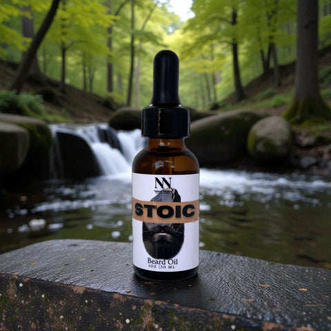 Stoic Beard Oil bottle on a rock beside a forest stream with a small waterfall