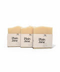 Three Plain Jane Unscented Handcrafted Soap bars wrapped in kraft paper sleeves, side by side on a white background