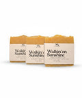 Three Walking on Sunshine Handcrafted Soap bars wrapped in kraft paper sleeves, side by side on a white background