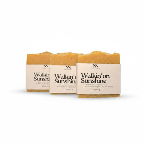 Three Walking on Sunshine Handcrafted Soap bars wrapped in kraft paper sleeves, side by side on a white background