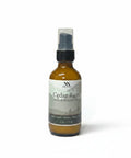 Cedar Rum Magnesium Lotion 2oz spray bottle with green and gray mountain-patterned label on a white background