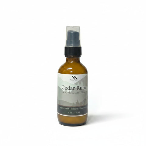 Cedar Rum Magnesium Lotion 2oz spray bottle with green and gray mountain-patterned label on a white background