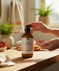 Hands dispensing Zen Magnesium Lotion from the pump bottle on a wooden bathroom countertop with plants and folded towels
