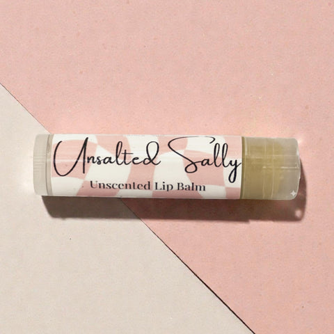 Unsalted Sally Fragrance-Free Olive Oil Lip Balm tube on a pink and beige geometric background