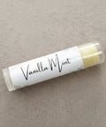 Vanilla Mint Olive Oil Lip Balm tube lying on a woven linen fabric