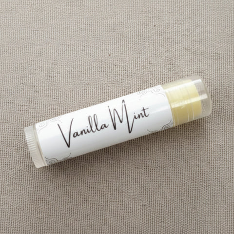 Vanilla Mint Olive Oil Lip Balm tube lying on a woven linen fabric
