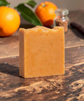 Walking on Sunshine Handcrafted Soap bar on a rustic wooden table with fresh oranges in the background
