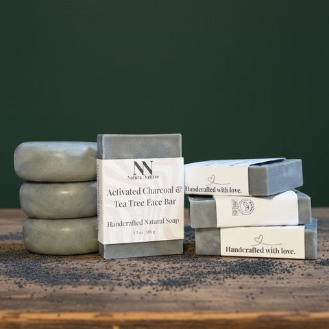 Charcoal & Tea Tree Face Bar Soap bars stacked on a wooden surface against a dark green background