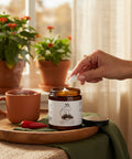 Natura+Nutrire Magnesium Cedar Rum cream jar on a wooden tray with a hand scooping product for muscle relief