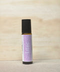 Body Oil Perfume Lilac rollerball bottle standing on a light wood surface