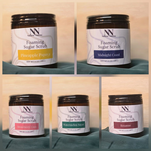 Foaming Sugar Scrub jars in five scents: Pineapple Papaya, Midnight Coast, Strawberry Coco, Watermelon Sugar, and Roxanne, on a teal fabric background