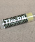 The OG Peppermint Lip Balm tube lying on a beige fabric background