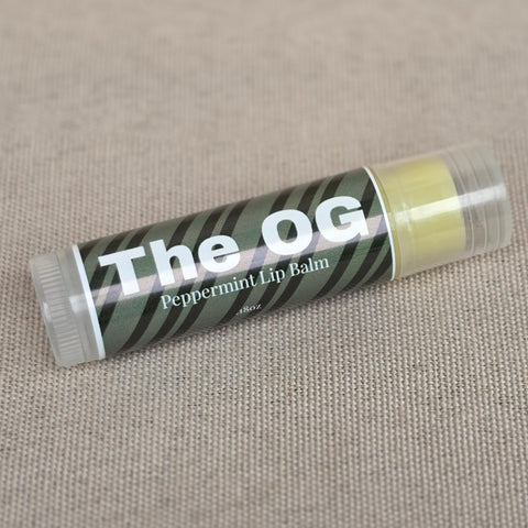 The OG Peppermint Lip Balm tube lying on a beige fabric background