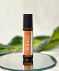 Umber Natural Botanical Fragrance rollerball bottle standing on a mirrored surface with green leaves in the background
