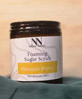 Foaming Sugar Scrub jar in Pineapple Papaya scent on a teal fabric background