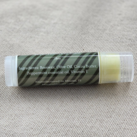 The OG Peppermint Lip Balm tube showing ingredients label listing beeswax, olive oil, cocoa butter, peppermint essential oil, and vitamin E