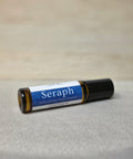 Body Oil Perfume Seraph rollerball bottle lying on its side on a linen surface