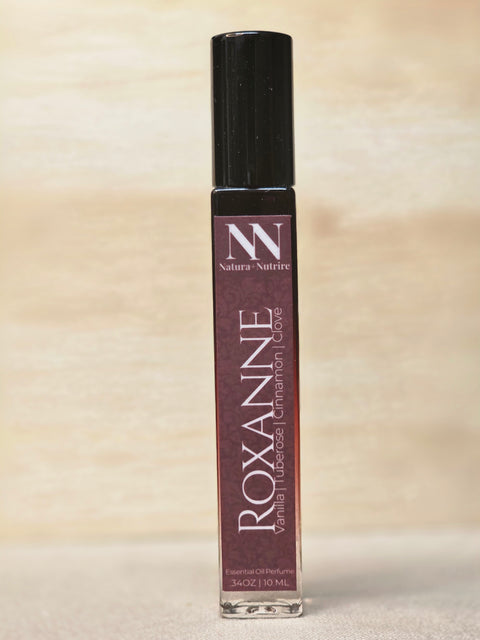 Roxanne Handcrafted Non-Toxic Fragrance rollerball bottle standing on a light wood surface