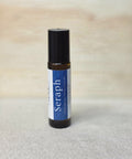 Body Oil Perfume Seraph rollerball bottle standing on a light wood surface with linen backdrop