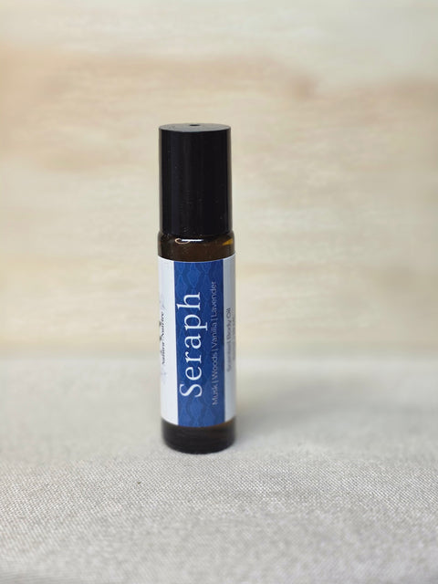 Body Oil Perfume Seraph rollerball bottle standing on a light wood surface with linen backdrop