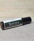 Revive Essential Oil Roller bottle lying on a linen surface