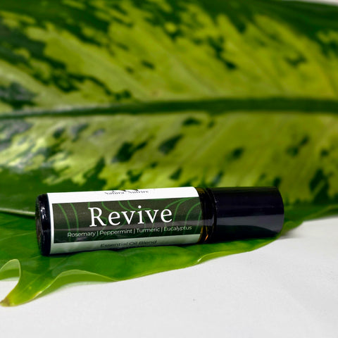 Revive Essential Oil Roller bottle lying on a large green leaf