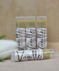 Four Vanille Vanilla Solid Perfume tubes arranged with a white tulip on a neutral background