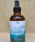 Bottle of Cedar Rum Magnesium Spray with a label on a neutral background