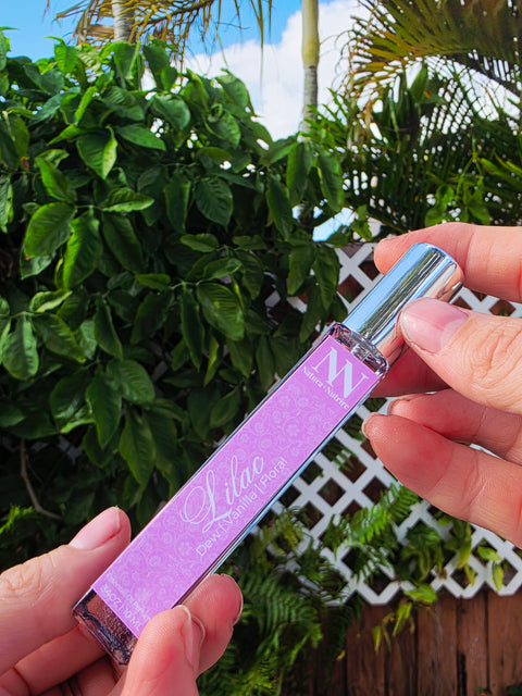 Hand holding the Lilac Handcrafted Non-Toxic Fragrance spray bottle against a lush green outdoor backdrop
