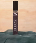 Obsidian Handcrafted Non-Toxic Fragrance spray bottle nestled in teal fabric against a warm background