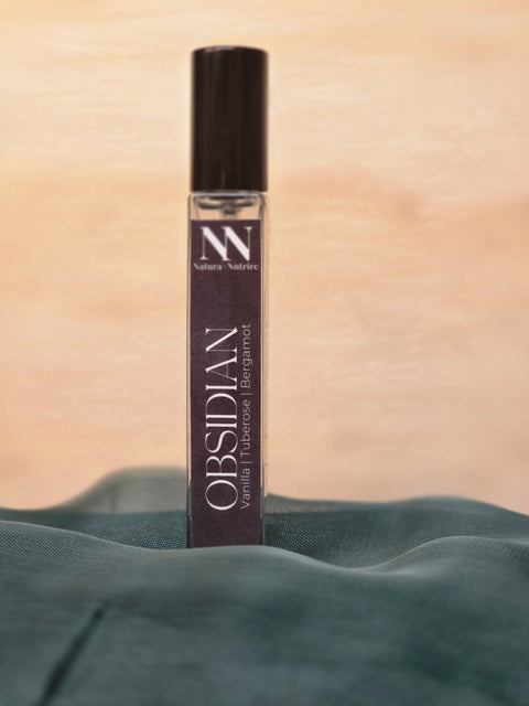 Obsidian Handcrafted Non-Toxic Fragrance spray bottle nestled in teal fabric against a warm background