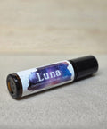 Body Oil Perfume Luna rollerball bottle lying on its side on a linen surface