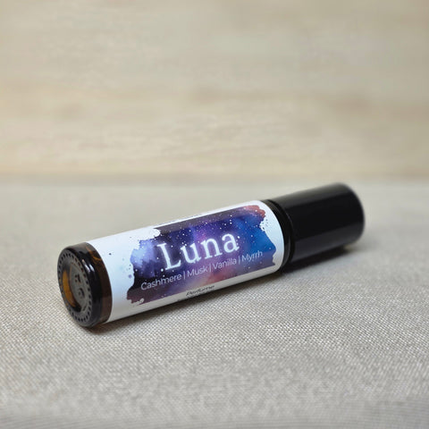 Body Oil Perfume Luna rollerball bottle lying on its side on a linen surface