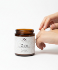 Person applying Zen Magnesium Cream to their hand next to the open jar on a white background