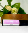 Lilac Natural Botanical Fragrance rollerball bottle lying in front of a wooden bowl and white lilac blossoms
