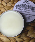 Open Repair & Nurture Skin Balm tin showing creamy balm texture, with the label visible on a woven surface